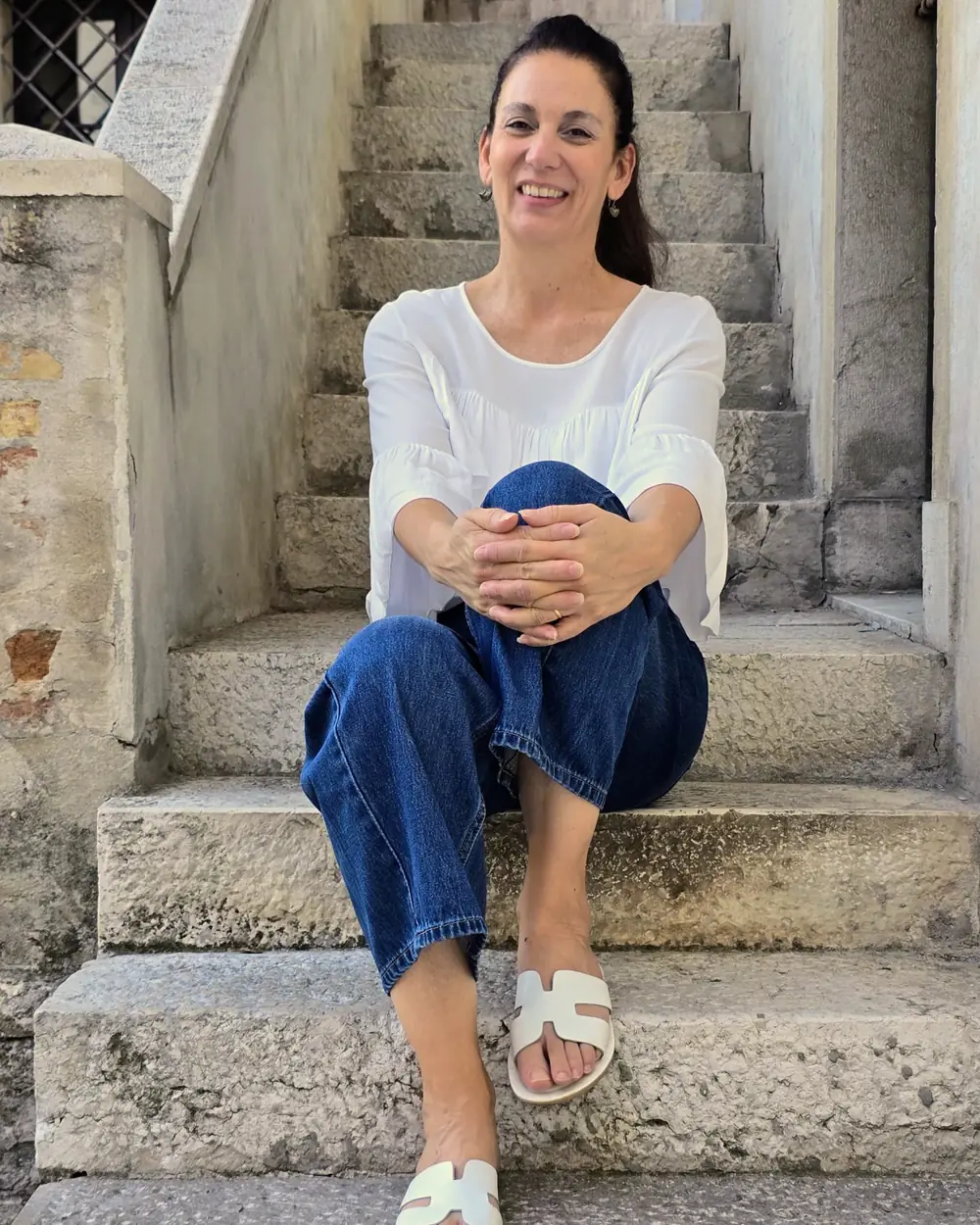Julieta Iglesias seduta su una scala di pietra, sorridente